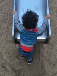 Rear view of woman sitting on slide at playground