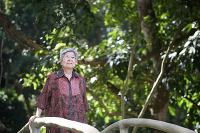 Portrait of young man standing against trees