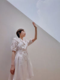 Low angle view of woman standing against white wall