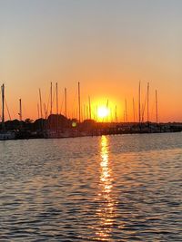 Silhouette sailboats in sea against sky during sunset