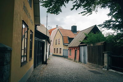 Alley amidst houses and buildings against sky