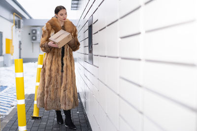 Full length of woman standing against wall