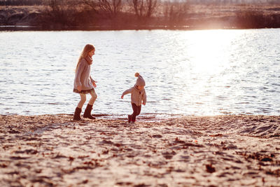 Happy girl with brother playing at lakeshore