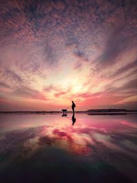 Silhouette man on sea against sky during sunset