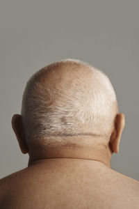 Shirtless senior man with short gray hair in front of gray background