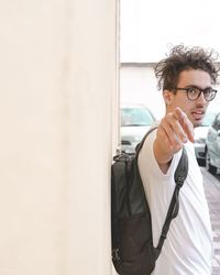 Portrait of young man standing against wall