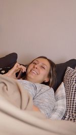 Portrait of smiling woman lying on sofa at home