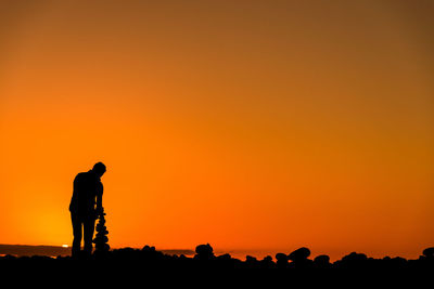 Silhouette man standing against orange sky