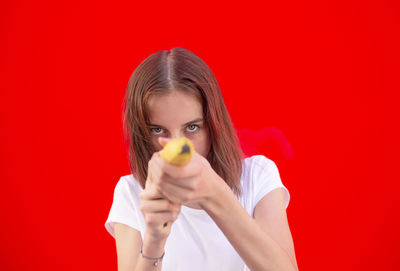 Portrait of woman holding red while standing against orange background