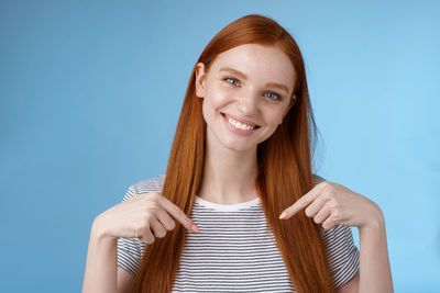 Portrait of a smiling young woman against blue background