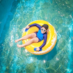 High angle portrait of girl sitting in pool raft at swimming pool
