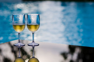 Two glasses of white wine put on table at swimming pool for holiday and summer drink concept.