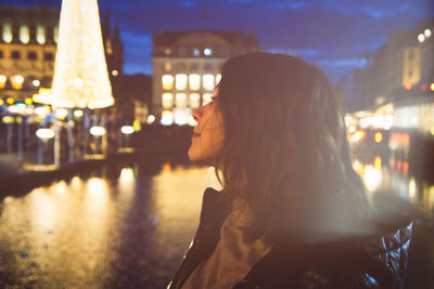 Portrait of woman standing in illuminated city at night