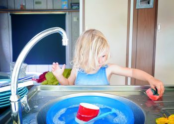 Cute girl washing sink in kitchen