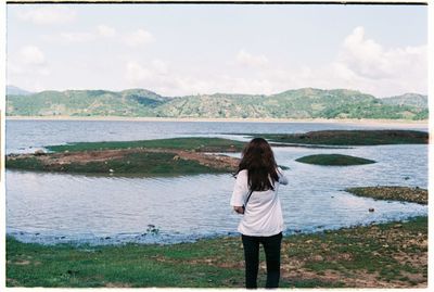 Rear view of man standing on lakeshore