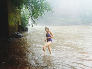 Woman walking in river at forest