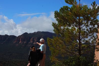 Couple standing on mountain against sky