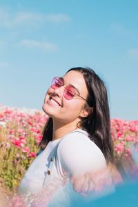 Smiling young woman on field against sky