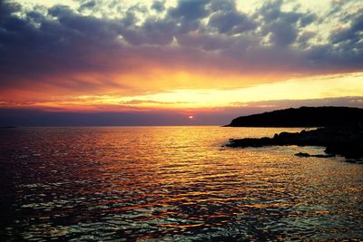 Scenic view of sea against dramatic sky during sunset