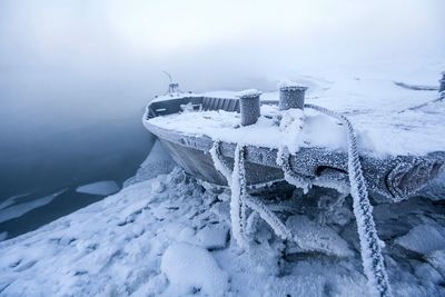 Frozen boat at lakeshore during foggy weather