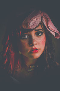 Close-up portrait of woman with make-up against black background