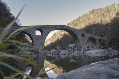 Arch bridge over river against sky