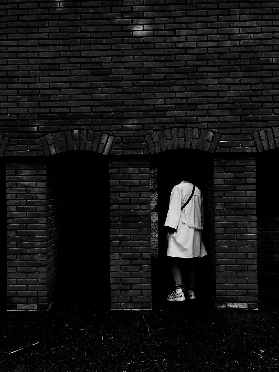 darkness, black, black and white, brick wall, brick, white, one person, architecture, full length, monochrome, built structure, monochrome photography, wall, light, wall - building feature, adult, standing, building exterior, women, lifestyles, leisure activity, casual clothing, night, men, outdoors, building