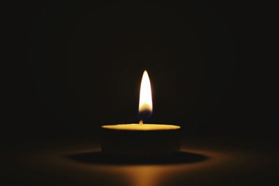 Close-up of lit candle in dark room