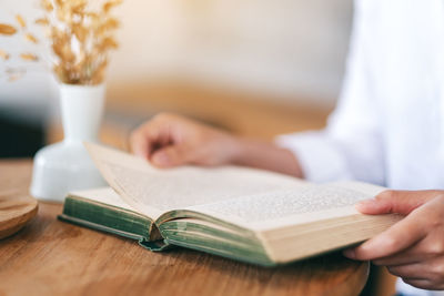 Midsection of businesswoman reading book at table in cafe