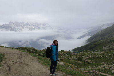 Rear view of man standing on mountain against sky