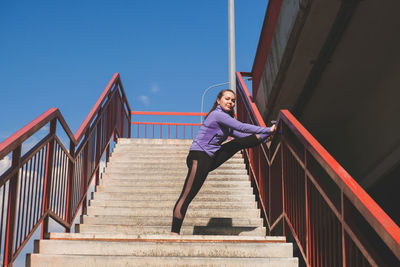 Low angle view of girl on staircase against sky