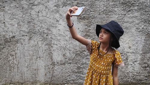 Young woman standing against wall