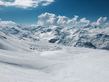 Scenic view of snow covered mountains against cloudy sky