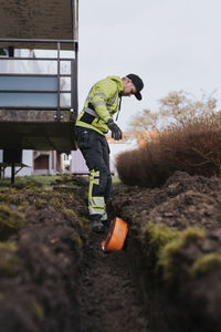 Male worker laying cable in trench