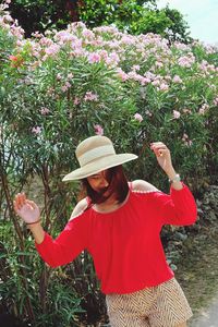 Tilt image of young woman standing against plants at park