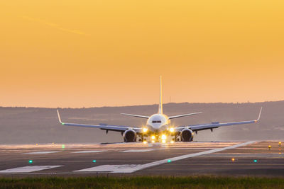 Airplane at airport runway during sunset