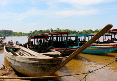 Abandoned boat moored in river against sky