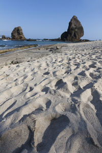 Surface level of rocks on beach against clear sky