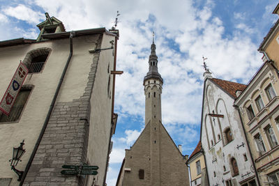 Low angle view of buildings and church against cloudy sky