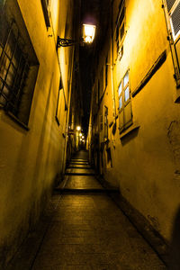 Empty alley amidst buildings in city at night