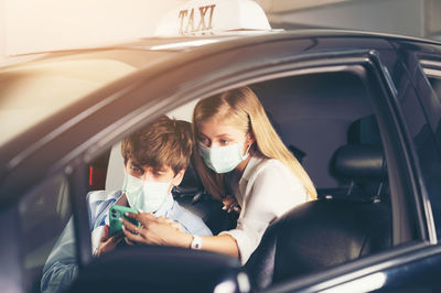 New normal. teenager sitting in the back of a car with a mask. young woman in a taxi protected