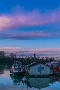 Boats moored in lake against sky during sunset