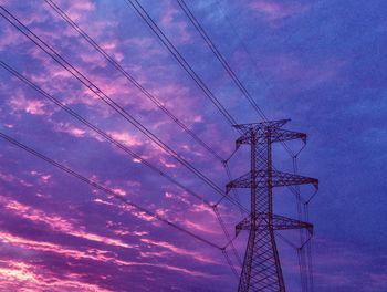 Low angle view of electricity pylon against cloudy sky