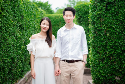 Portrait of smiling couple holding hands while standing in park