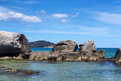 Rocks by sea against blue sky