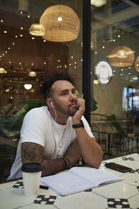 Young man looking away while sitting in restaurant