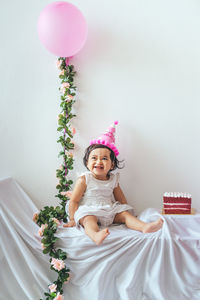 Full length of cute girl sitting with balloons