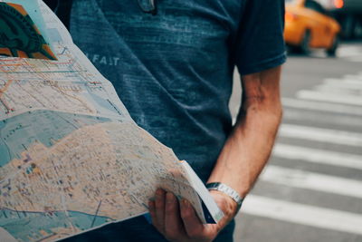 Midsection of man reading book on paper