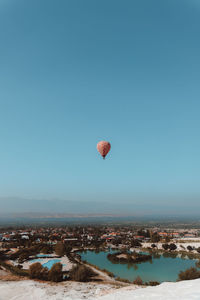 Hot air balloon flying over land against clear sky