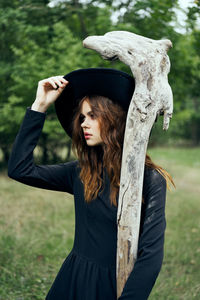 Portrait of young woman standing against trees